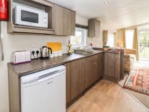 a kitchen with wooden cabinets and a microwave at Broad Down in Birtsmorton +8 photos