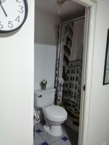 a bathroom with a toilet and a clock on the wall at Lopez House in Lima