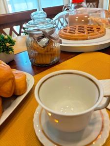 - une tasse de café assise sur une table avec des pâtisseries dans l'établissement B&B Rosa dei Venti, à Sorso