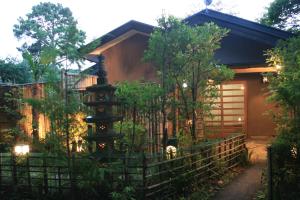 uma casa com uma cerca em frente em Rokugatsu-no-Mori Auberge em Sano