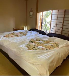 een wit bed met veel kussens erop bij Rokugatsu-no-Mori Auberge in Sano