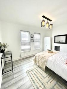 a bedroom with a bed and a desk and two windows at Spacious Modern Victorian House in Rochester in Wainscot