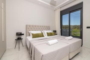 a white bedroom with a large bed with a large window at Royal View Villa - Private Pool & Hot Tub in Zakynthos Town