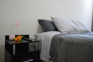 a bedroom with a bed with a nightstand with a table with a flower on at Hermoso departamento en exclusivo Condominio in Arequipa