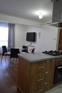 a kitchen with a stove and a table with chairs at Hermoso departamento en exclusivo Condominio in Arequipa