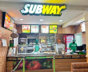 two people standing behind a counter in a subway restaurant at Belavista Hotel in Itaberaba