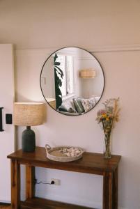 a mirror on a wall above a table with a lamp at The Byron Bay Guesthouse in Byron Bay