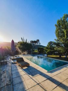 una piscina con banco y sombrilla en Cabañas Andaluhe en Villa Carlos Paz