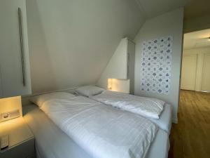 1 cama blanca en una habitación con 2 lámparas en Beautiful wellness villa with sauna, on a holiday park on the Tjeukemeer, en Delfstrahuizen