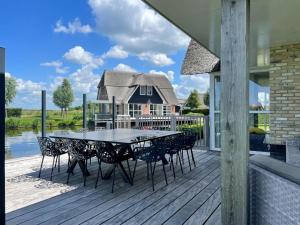 una terraza con mesa y sillas en una casa en Beautiful wellness villa with sauna, on a holiday park on the Tjeukemeer, en Delfstrahuizen