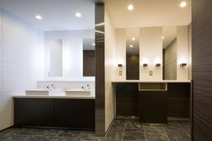 a bathroom with two sinks and two mirrors at Hotel Sunroute Chiba in Chiba