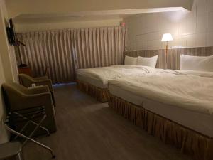 ein Hotelzimmer mit 2 Betten und einem Stuhl in der Unterkunft 東石民宿 湛藍海寓 Azure Seaside House in Dongshi