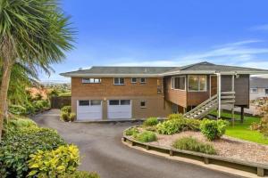 a house with a palm tree and a driveway at Aww Sheep-Uninterrupted Panoramic View with Spa in Rotorua