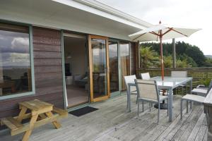 a patio with a table and chairs and an umbrella at Aww Sheep-Uninterrupted Panoramic View with Spa in Rotorua
