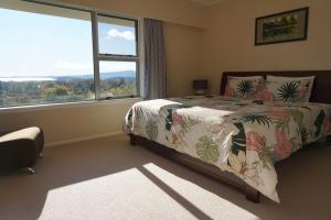 a bedroom with a bed and a large window at Aww Sheep-Uninterrupted Panoramic View with Spa in Rotorua