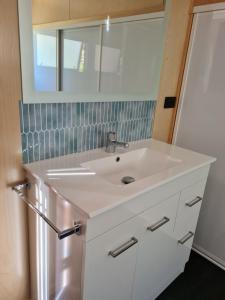 La salle de bains est pourvue d'un lavabo blanc et d'un miroir. dans l'établissement Kaiteriteri Tiny Home, à Kaiteriteri