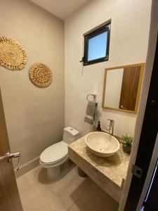 a bathroom with a sink and a toilet and a mirror at Hermosa casa para conocer León in León
