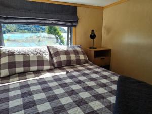 a bedroom with a checkered bed and a window at Kaiteriteri Tiny Home in Kaiteriteri