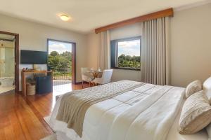 - une chambre avec un grand lit blanc et une table dans l'établissement Villa Boréal Hostellerie, à Águas de Lindóia