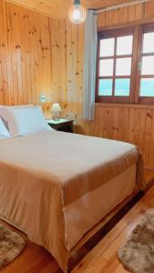 a bedroom with a large bed in a room with wooden walls at Chalé Campos Da Serra in São José dos Ausentes