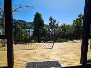 a wooden deck with a black fence and trees at Kaiteriteri Tiny Home in Kaiteriteri
