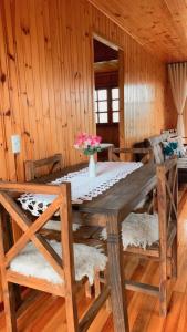 ein Esszimmer mit einem Holztisch und Stühlen in der Unterkunft Chalé Campos Da Serra in São José dos Ausentes