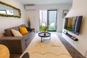 a living room with a couch and a tv at Glamorous 2 bed CBD townhouse w/King bed in Christchurch