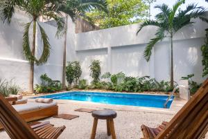 a swimming pool in a backyard with palm trees at Rodina - Hotel Boutique in Playa del Carmen