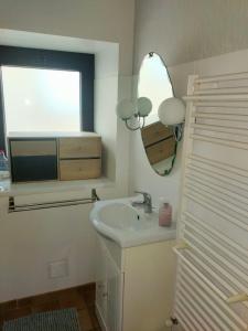 een badkamer met een wastafel, een spiegel en een raam bij La Grange de Lili in Figeac