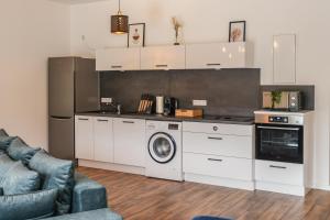 cocina con armarios blancos, lavadora y secadora en Penthouse I 85 qm I Boxspring I Balkon I Nespresso, en Oberharmersbach