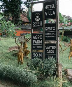 a sign for a hotel with statues in the grass at Umadhatu Resort by Amerta in Tabanan