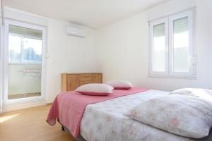 a white bedroom with a bed with pink sheets and windows at Apartments with WiFi Split - 20900 in Split
