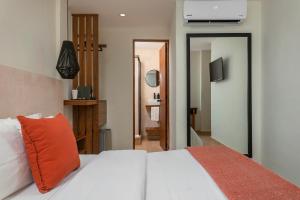a bedroom with a white bed with an orange pillow at Rodina - Hotel Boutique in Playa del Carmen +35 photos