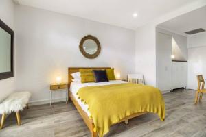 1 dormitorio con 1 cama con manta amarilla y espejo en Stylish Studio close to City, en Melbourne