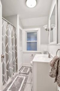 ein weißes Bad mit einem Waschbecken und einer Dusche in der Unterkunft Charming Cuse home close to downtown & university in Syracuse
