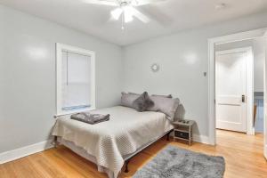 - une chambre blanche avec un lit et un ventilateur de plafond dans l'établissement Charming Cuse home close to downtown & university, à Syracuse