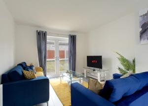 a living room with two blue couches and a tv at Free Parking Large House Huyton Golf Club M57 in Roby