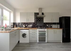 a kitchen with white cabinets and a stove top oven at Free Parking Large House Huyton Golf Club M57 in Roby