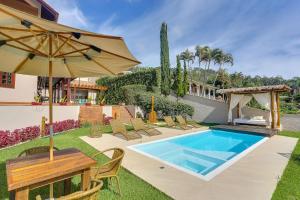 einen Hinterhof mit Pool, Tisch und Sonnenschirm in der Unterkunft Villa Boréal Hostellerie in Águas de Lindóia