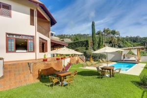 einen Hinterhof mit einem Pool, Tischen und Sonnenschirmen in der Unterkunft Villa Boréal Hostellerie in Águas de Lindóia