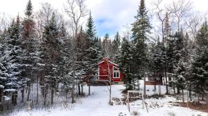 Saint-RaymondにあるLes Chalets Tourisma - Chalet dans les bois avec lac privé - Le Colibriの雪の中の赤い小屋