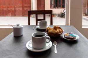 a table with two cups of coffee and a basket of croissants at Ñañitas Tampu Wasi in Maimará