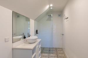 ein weißes Bad mit einem Waschbecken und einer Dusche in der Unterkunft Beyond Bliss Guesthouse 2 in Bright