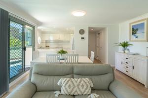 a living room with a couch and a kitchen at Sails Apartments in Forster