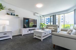 a living room with white furniture and a flat screen tv at Sails Apartments in Forster