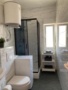 a white bathroom with a shower and a toilet at Sea View Apartments in Grebaštica