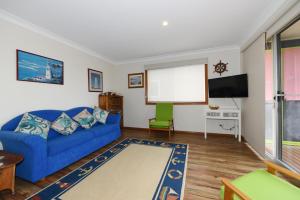 sala de estar con sofá azul y TV de pantalla plana en Aqua Vincentia - Belle Escapes Jervis Bay, en Vincentia