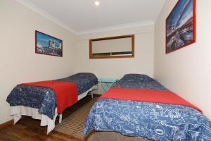 a bedroom with two beds and a mirror at Aqua Vincentia - Belle Escapes Jervis Bay in Vincentia
