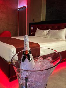 a bottle of champagne in a glass in front of a bed at Motel Qatro in Ensenada