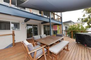 una terraza de madera con mesa y sillas de madera en Aqua Vincentia - Belle Escapes Jervis Bay, en Vincentia